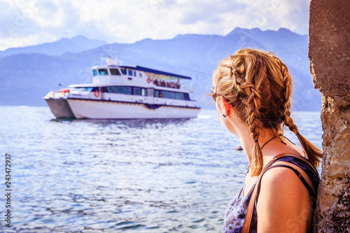 Young girl is looking at a ar ferry on an Italian lake photo