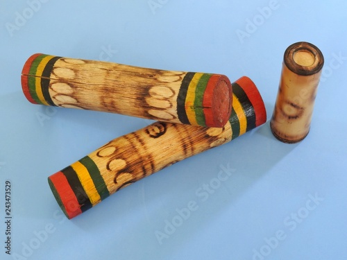 Close-up of three “ganzás”, a Brazilian rattle used as a percussion instrument, especially in samba music. These are handmade and made of bamboo. Blue background. photo