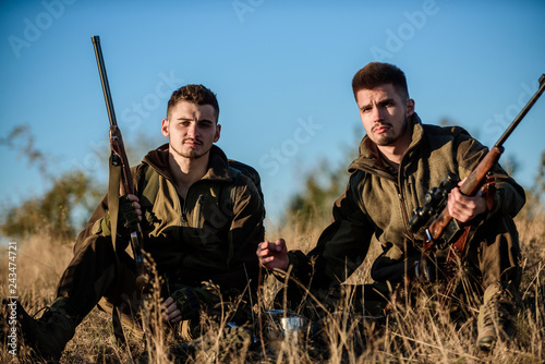 Hunting with friends hobby leisure. Hunters with rifles relaxing in nature environment. Hunters satisfied with catch drink warming beverage. Hunters friends enjoy leisure. Rest for real men concept