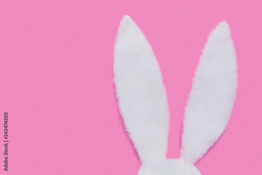 Rabbit ears made of white fur on pink pastel background. The concept of Easter