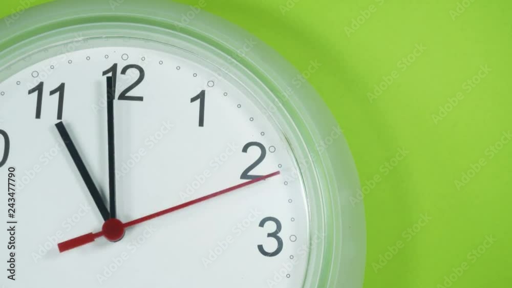 Close-up White clock with Black numbers and arrows, Start time 10.45 on Green background, Time Lapse Clock walking 20 minute. Close-up White clock with Black numbers and arrows, Start time 10.45 on Green background, Time Lapse Clock walking 20 minute.