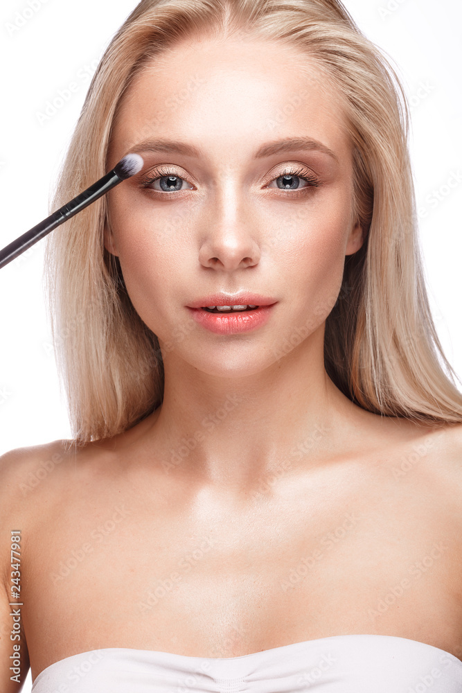Beautiful young girl with a light natural make-up,eye shadow brush and nude manicure. Beauty face.