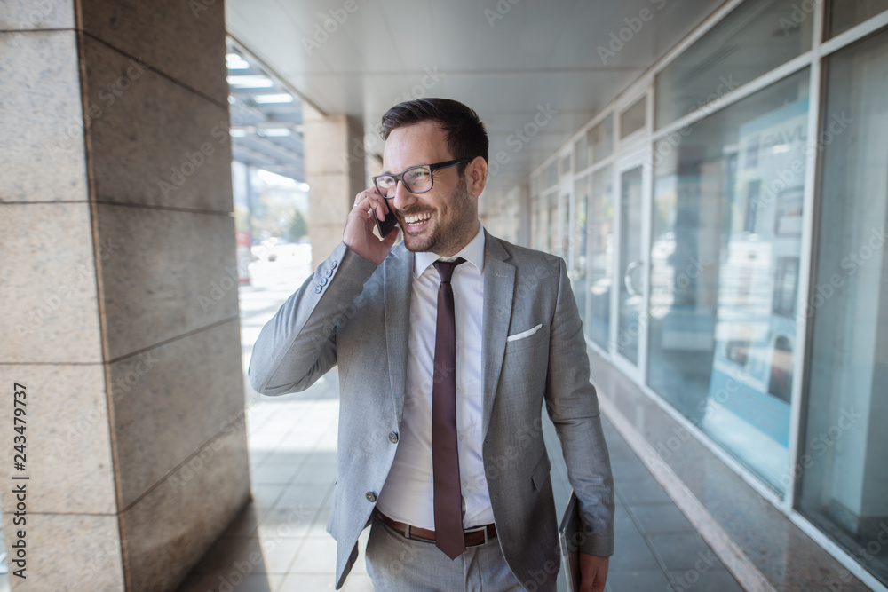 Successful young white collar worker using smart phone for business talk while standing in front of business center. In other hand tablet. Successful young white collar worker using smart phone for business talk while standing in front of business center. In other hand tablet.