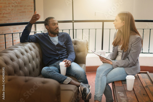 Co workers casually discussing ideas on sofa in modern workplace photo