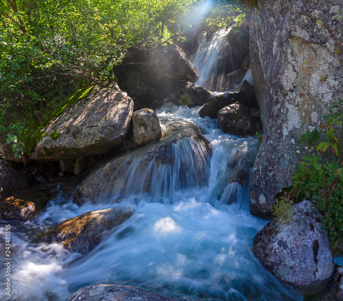 Water filled with mineral salts, flows impetuously among the stones of a stream on the slopes of Mount Rosa in Piedmont, Italy photo