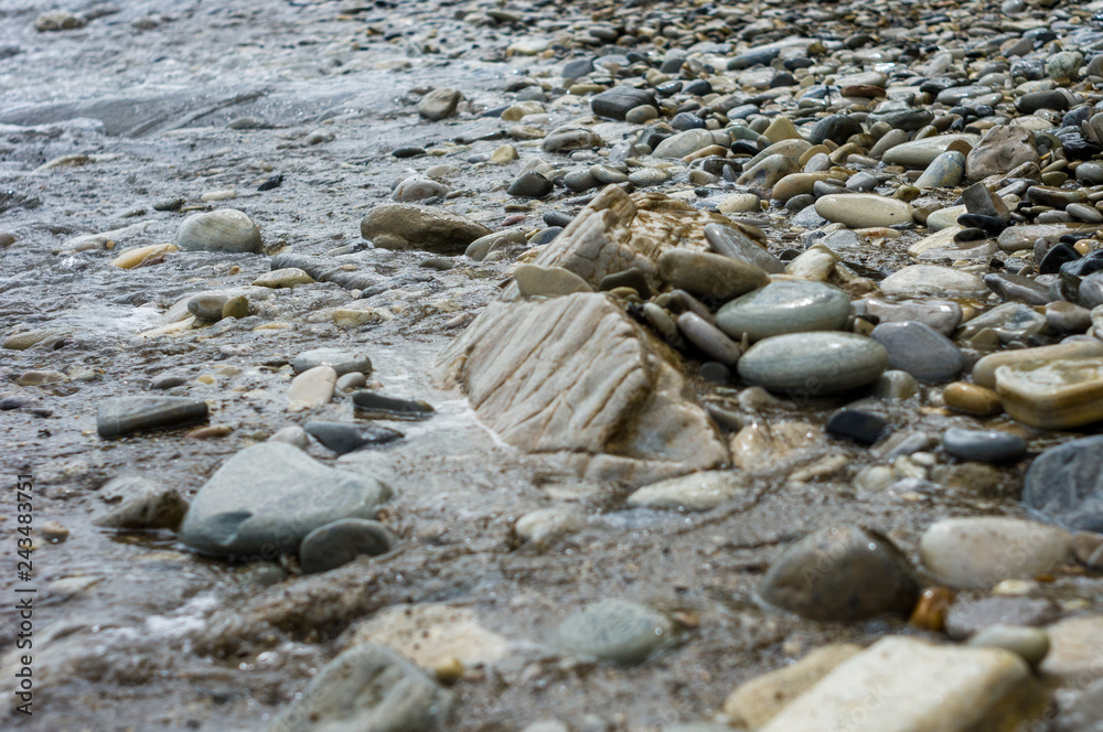 pebble stones on the sea beach, the rolling waves of the sea with foam pebble stones on the sea beach, the rolling waves of the sea with foam