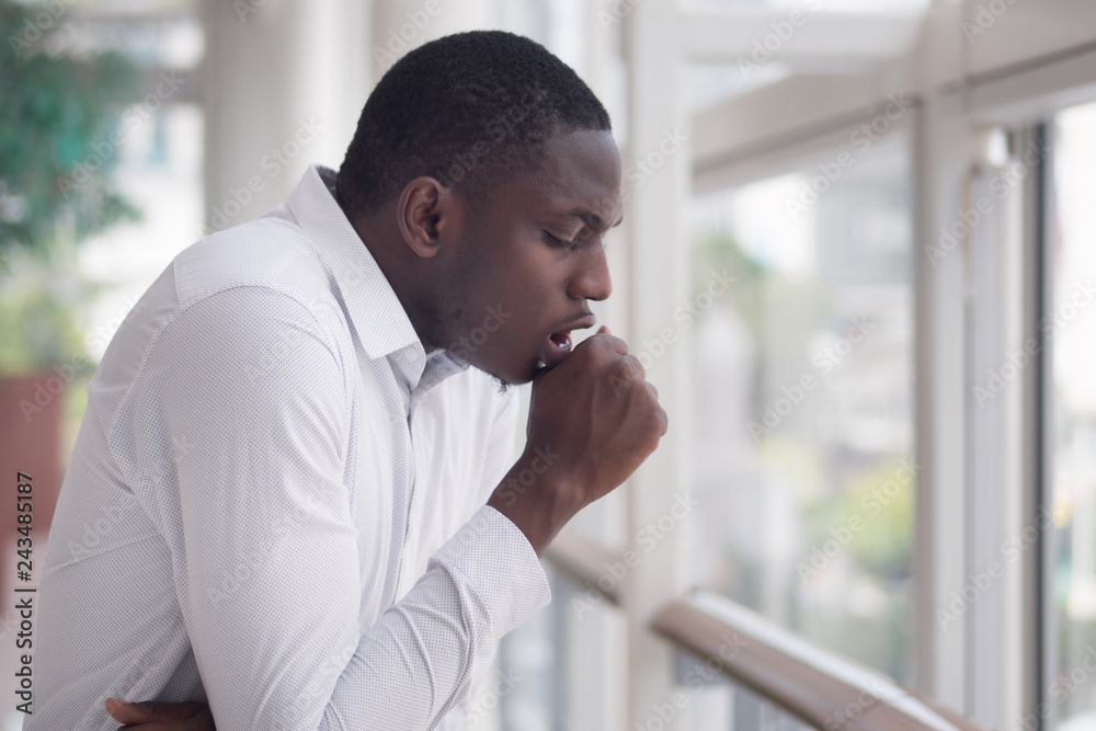 Sick African man coughing; Portrait of ill black man cough due to cold, flu, allergy, polluted