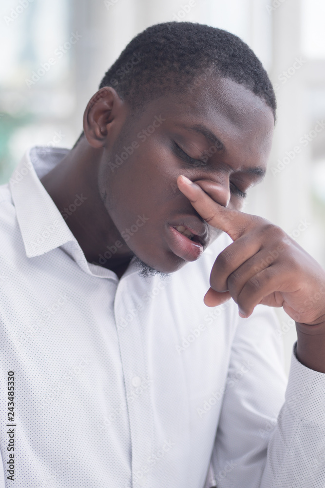 Sick African man with runny nose; Portrait of ill black man suffering