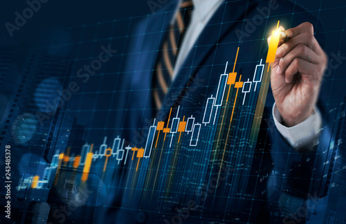 Business growth, progress or success concept. Businessman is drawing a growing virtual hologram stock bar chart on dark blue background.