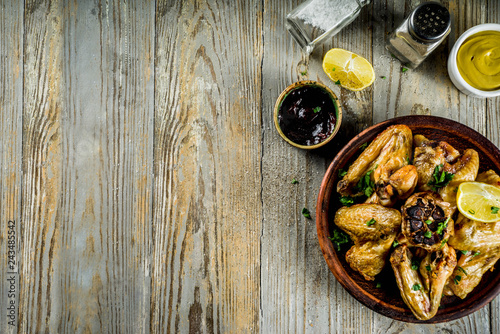 Grilled bbq chicken wings with sauces and spices, wooden background copy space top view
