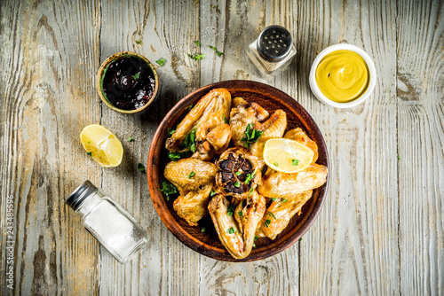 Grilled bbq chicken wings with sauces and spices, wooden background copy space top view