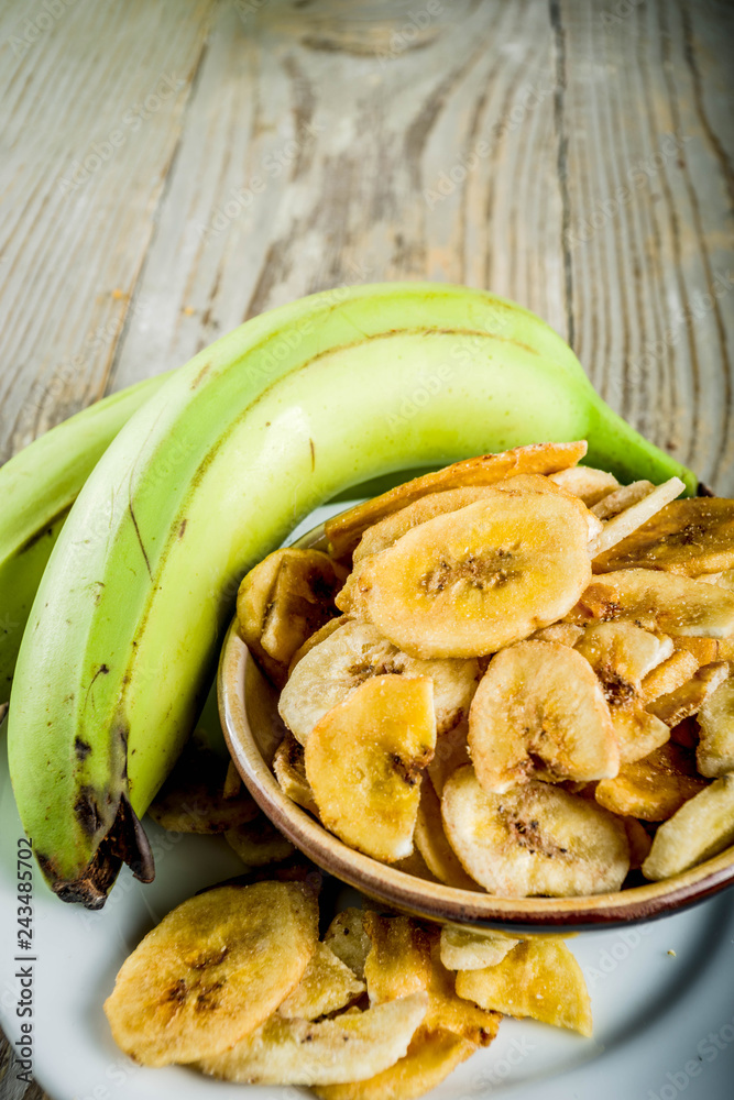 Dried bananas plantains with fresh bananas, wooden background copy space