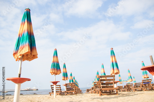 Aerial view to sandy beach of Adriatic sea in Albania, full of umbrellas and sunbeds, Port of Durres in horizon.