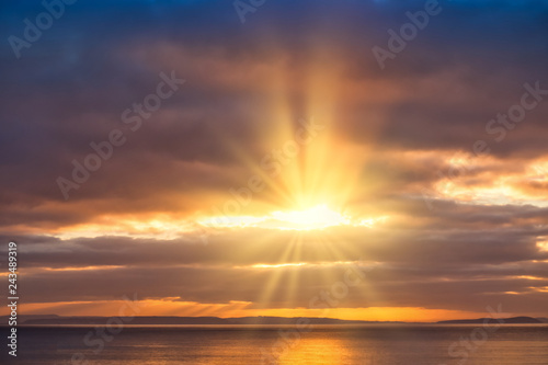 Golden Sun Rays Shining through Dark Clouds onto the Sea © tinasdreamworld