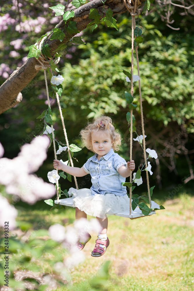 Little cute girl swinging on teeter in summer park, portrait