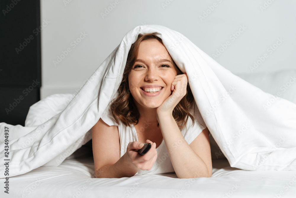 Attractive young woman sitting on bed at home Attractive young woman sitting on bed at home