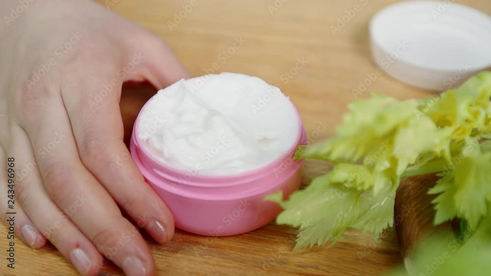 macro finger takes cream from jar on table with greens macro finger takes cream from jar on table with greens