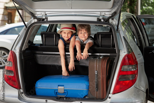 little brother and sister sitting in the back of a car.