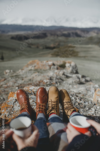 Travel trekking leisure. Couple in hiking boots with cups having fun and enjoying wonderful breathtaking mountain view
