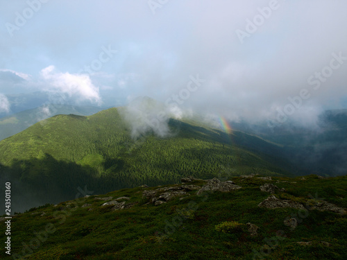 Picturesque landscape of Carpathian mountains with rainbow over them. Heaven kitchen prepares rainy whether in summer in mountains. Eastern Carpathians, Ukraine