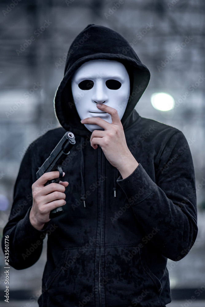 Mystery hoodie man in white mask holding gun. Crime and violence concepts  Stock Photo | Adobe Stock