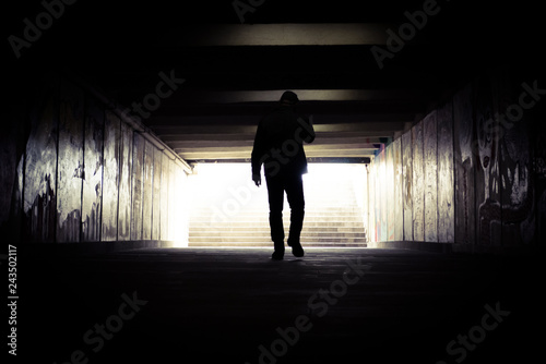 A man going to the end of a tunnel to the light. Silhouette of a man going to light in the end of a tunnel.