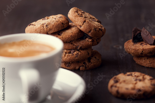 Homemade chocolate chip cookies and a cup of coffee on dark old wooden table. Sweet dessert.
