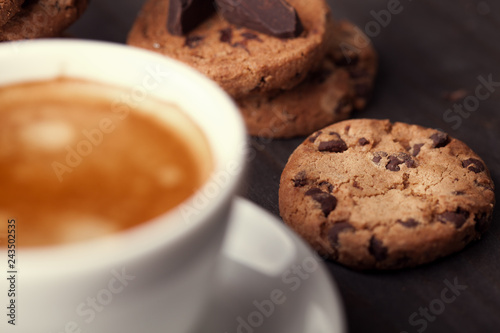 Homemade chocolate chip cookies and a cup of coffee on dark old wooden table. Sweet dessert.