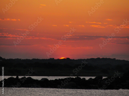 Sunset with a orange red and yellow sky in a river ocean lake sea 