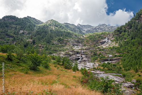 Water filled with mineral salts, flows impetuously among the stones of a stream on the slopes of Mount Rosa in Piedmont, Italy photo