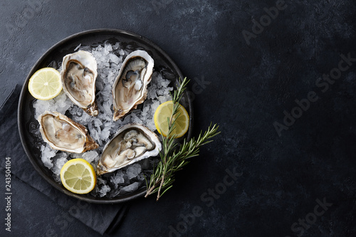 Fresh oysters in a plate with ice on black background