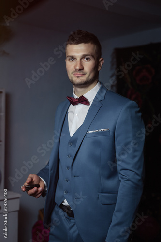 groom fees at the wedding. National traditional rural setting. A man in a suit and a bow tie is thinking with car keys in his hands.