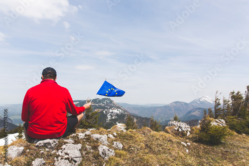 hiker with red sweater and flag from the european union outdoor somewhere in the austrian alps