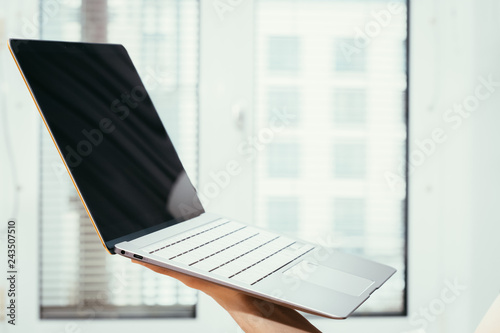 Young freelancer is holding up a thin elegant notebook photo