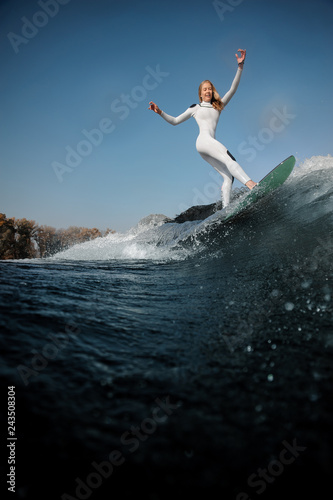 Side view blonde girl standing on the wakeboard