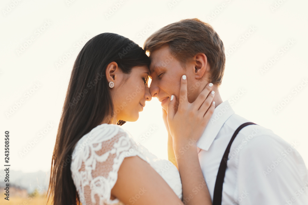 Loving couple dressed in white, ready to kiss outdoors with clos Loving couple dressed in white, ready to kiss outdoors with clos