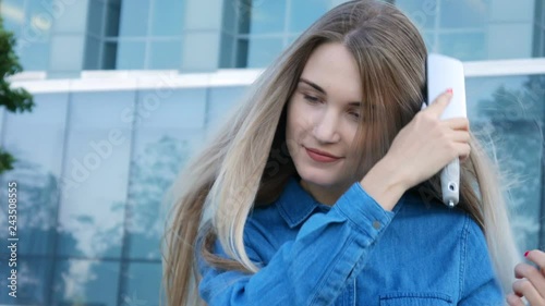 Charming lady trying to comb brush her hair in a heavy wind