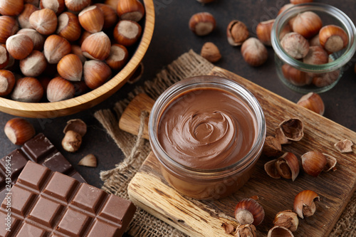 Chocolate spread, nuts and chocolate bars on table