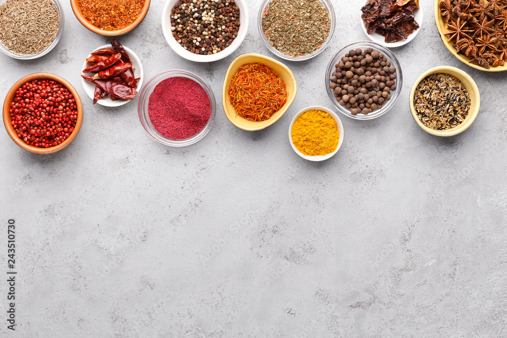 Indian spices in bowls on grey background