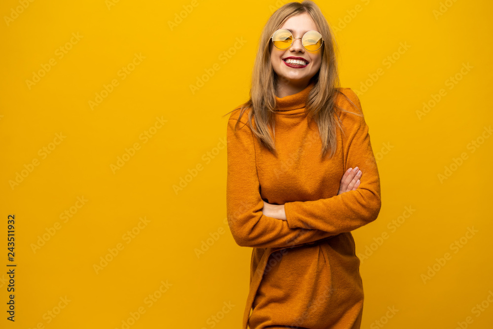 Excited young woman in orange dress, widely smiling, looking at camera. Isolated on yellow background Excited young woman in orange dress, widely smiling, looking at camera. Isolated on yellow background