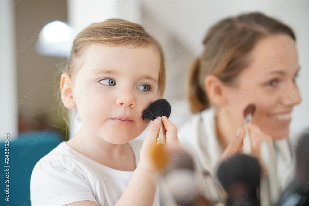 Mother and young daughter playing and applying make up together Mother and young daughter playing and applying make up together