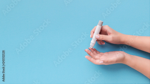 Woman using glucometer on blue background, top view