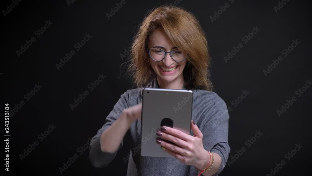 Closeup portrait of attractive caucasian middle-aged woman having a video call on the tablet casually with the background isolated on black