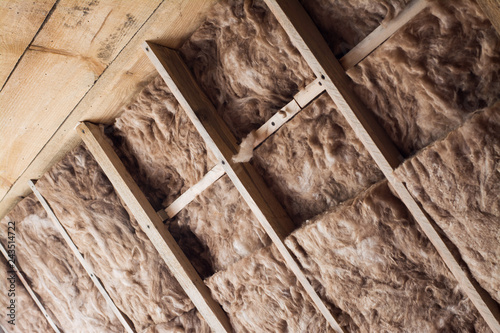 Glass wool in a wooden frame on a inclined wall near the wooden ceiling at attic. Warming the house with fiberglass. photo