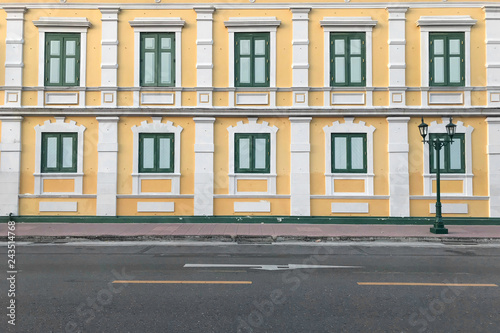 Yellow walls of building with windows beside road.