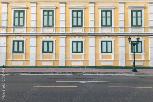 Photography Yellow walls of building with windows beside road.