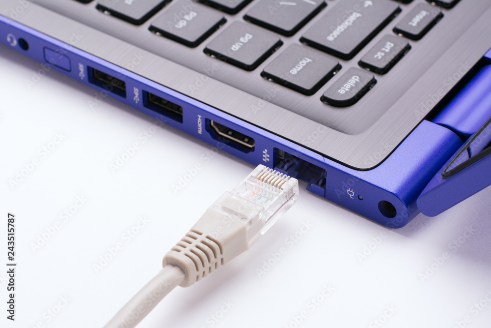 White LAN Internet cable near the port of a modern blue laptop White LAN Internet cable near the port of a modern blue laptop