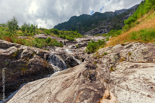 Panoramic view of a stream flowing on the steep rocky walls of Monte Rosa in Piedmont, Italy.
