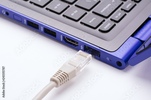 White LAN Internet cable near the port of a modern blue laptop