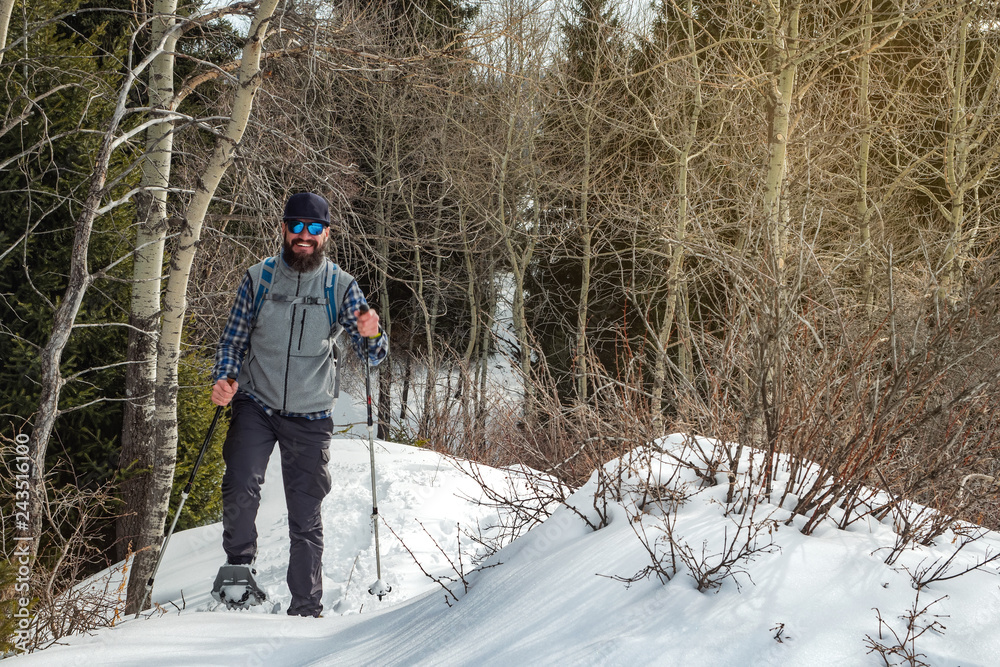Hiker in the mountains walks on snowshoes. The man is alone in the forest. Winter mountain tourism